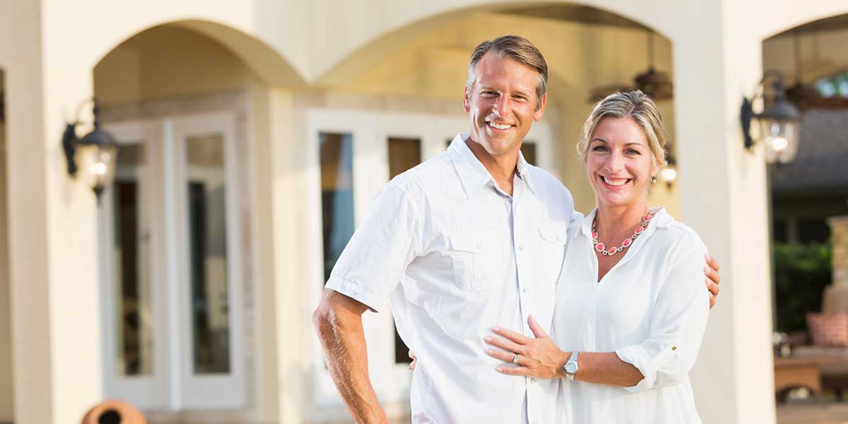 Smiling couple in front of house